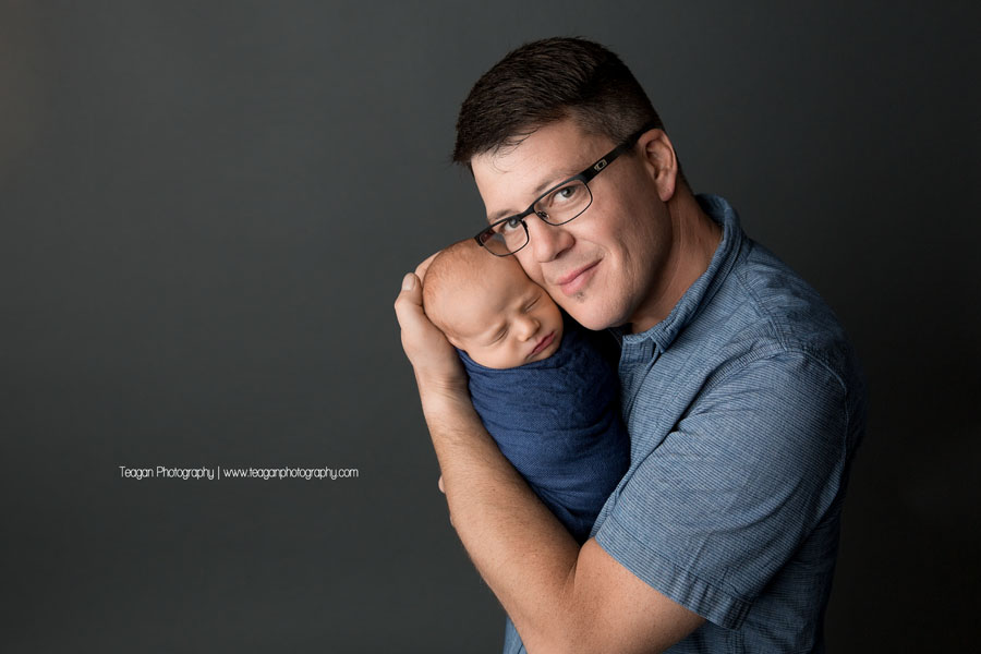 A new father snuggles his newborn baby boy during an Edmonton photography shoot