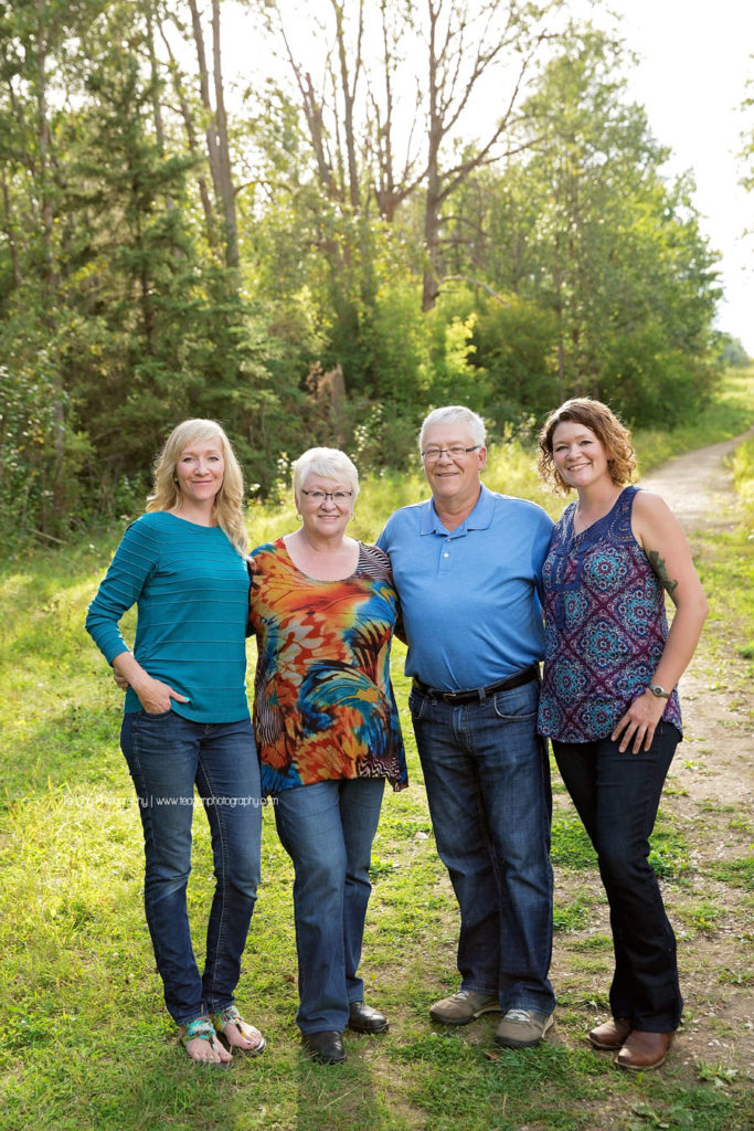Grown up children pose with their senior parents in a sunlit forest