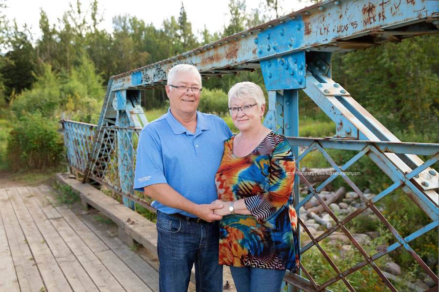 A senior couple stand together on the blue bridge at Larch Sanctuary