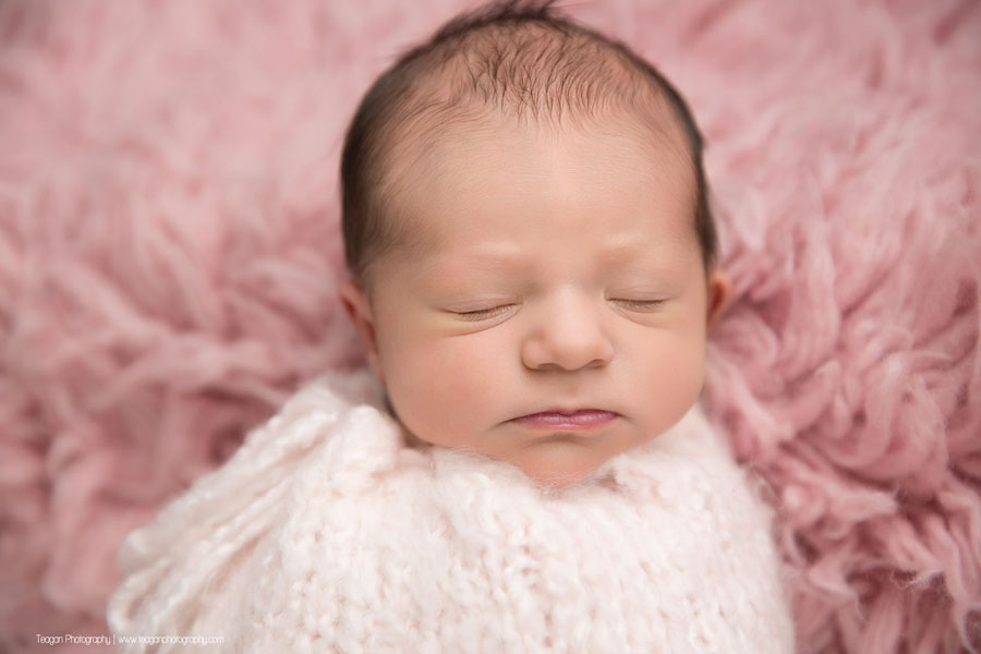 An Edmonton newborn baby sleeps on a pink rug in a pink scarf