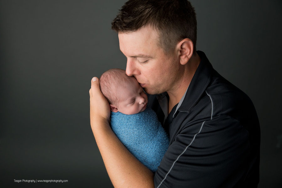 A new father kisses the head of his baby boy