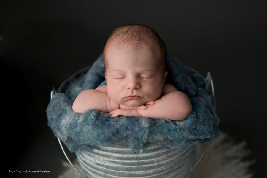 An Edmonton newborn baby sleeps in a metal bucket stuffed with denim blue wool fluff