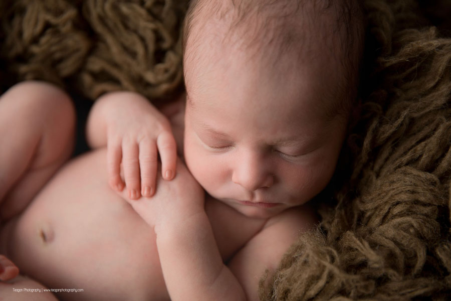 A close up of a baby boy asleep on a brown rug