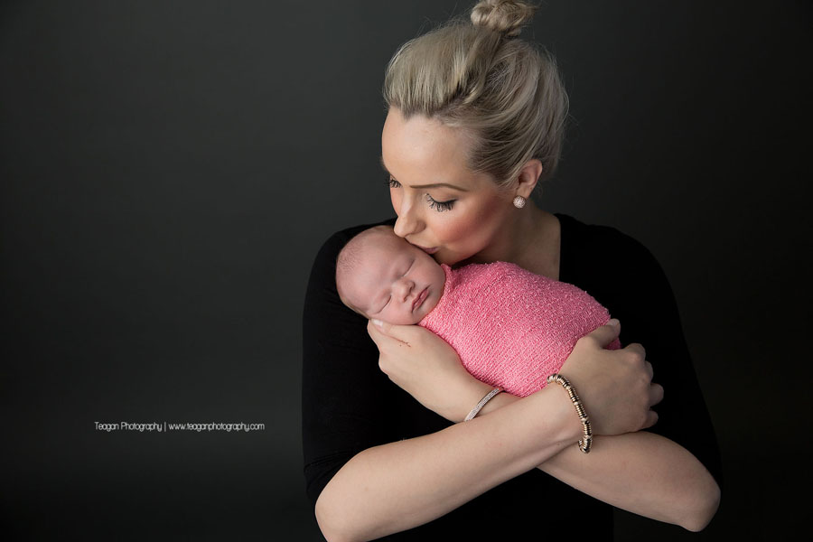 A new mother kisses her brand new baby girl who is wrapped in a pink blanket