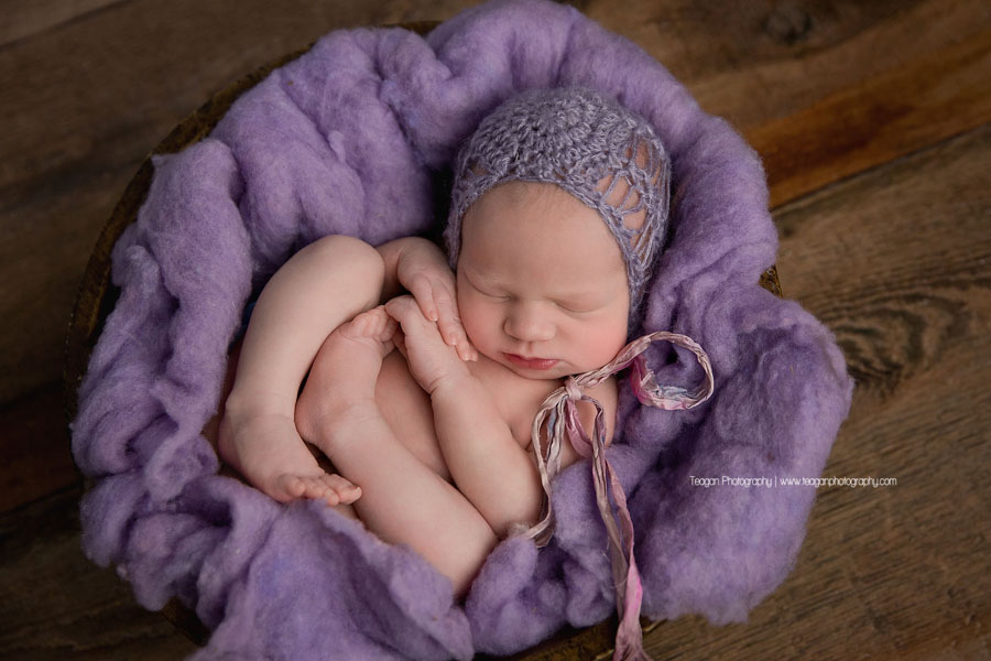 A newborn girl sleeps in purple fluff during an Edmonton newborn photography session