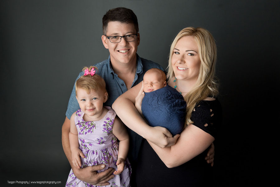 A new family of four pose together during an Edmonton newborn photography session