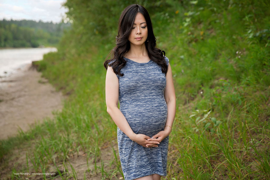 A pregnant Chinese woman hugs her belly during maternity photos in Edmonton
