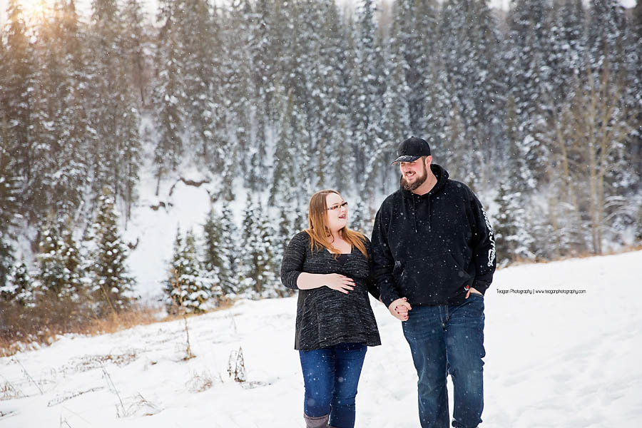 Posing together in the snow is a couple pregnant with their first child