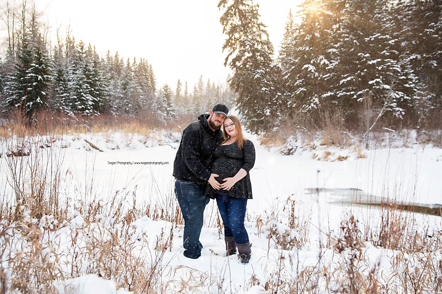 Couple posing in falling snow near Snow Valley Edmonton for outdoor maternity portrait