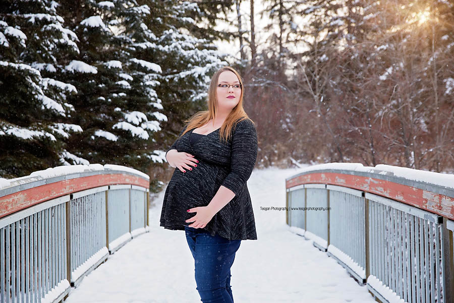 Couple posing in falling snow near Snow Valley Edmonton for outdoor maternity portrait