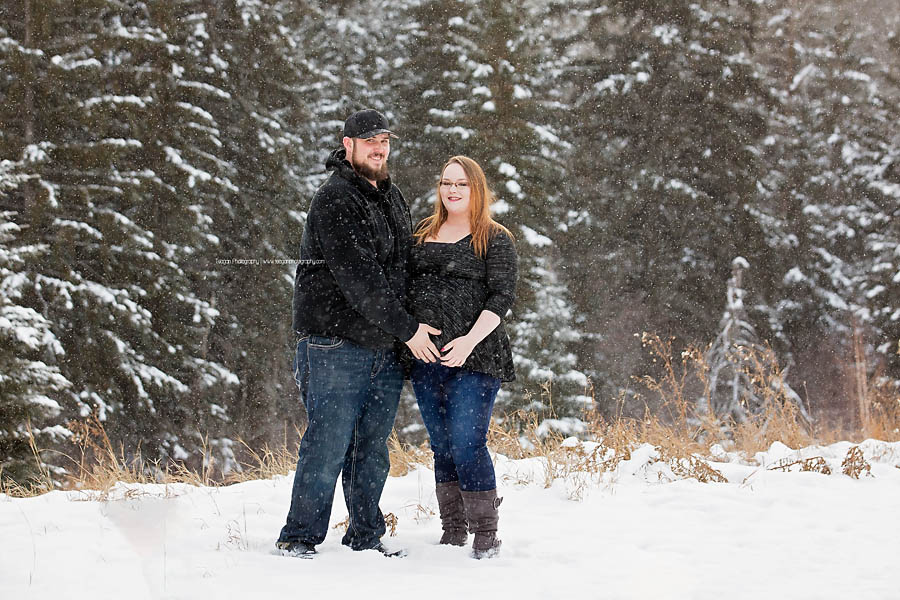 Couple posing in falling snow near Snow Valley Edmonton for outdoor maternity portrait