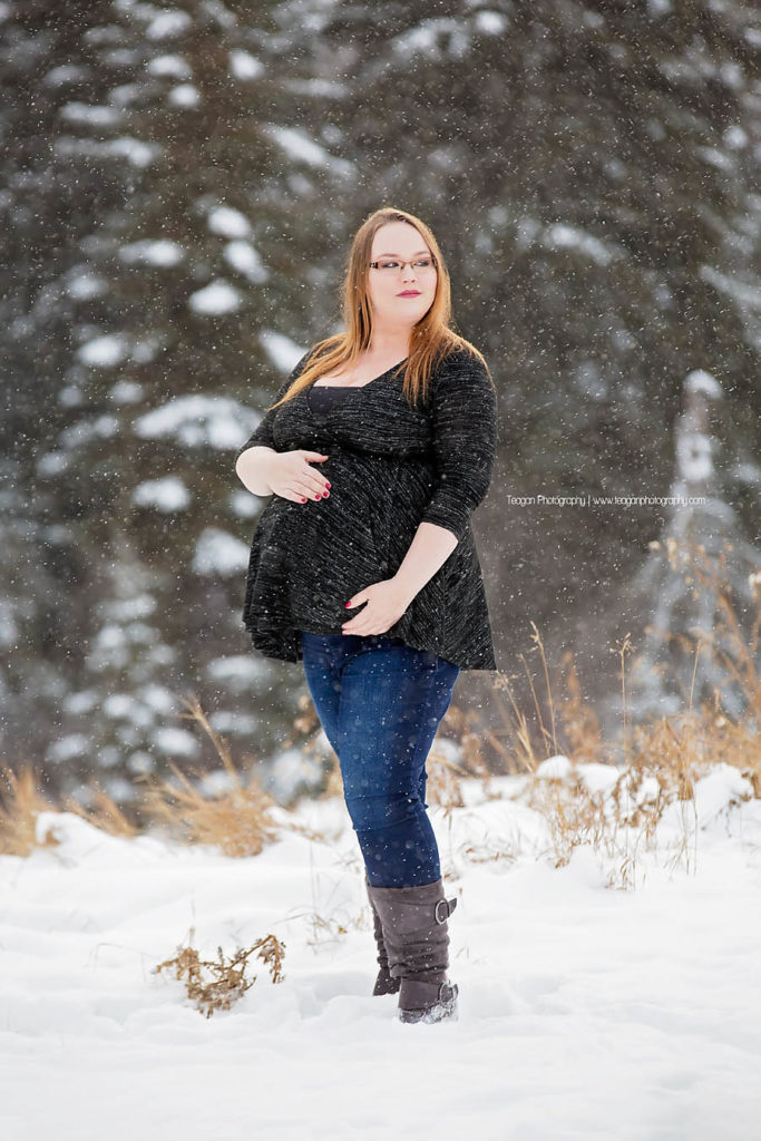YEG maternity photographer capturing outdoor winter pregnancy photos with snowflakes falling