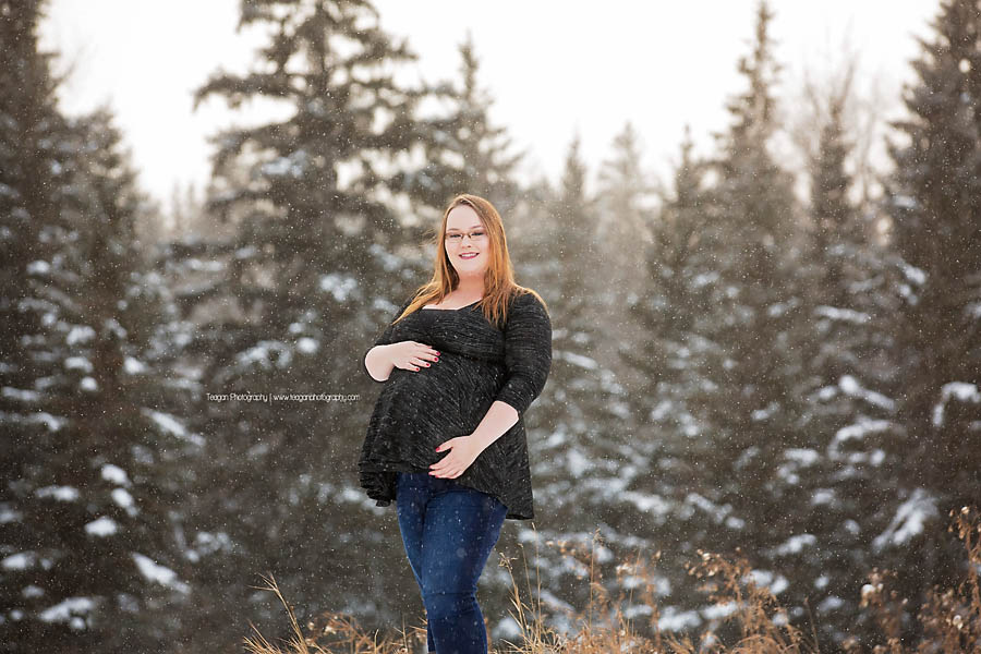YEG maternity photographer capturing outdoor winter pregnancy photos with snowflakes falling