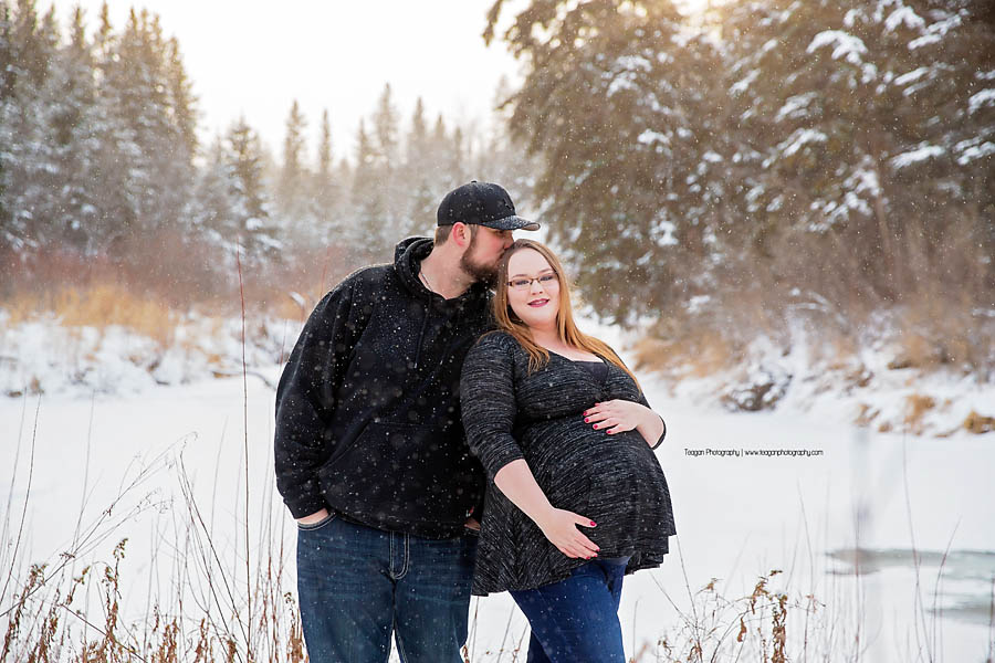 YEG maternity photographer capturing outdoor winter pregnancy photos with snowflakes falling