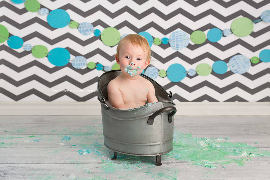 bathing in a small metal bathtub is a one year old birthday boy after his Edmonton cake smash