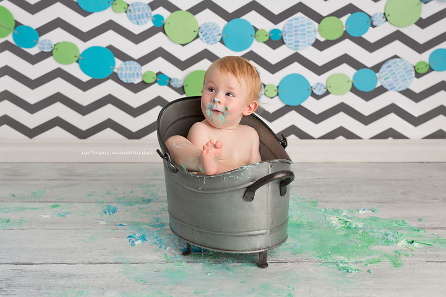 bathing in a small metal bathtub is a one year old birthday boy after his Edmonton cake smash