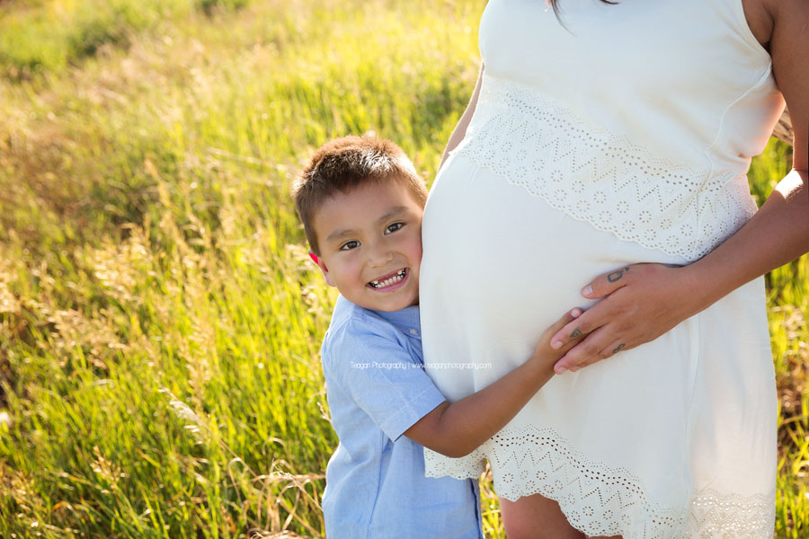 A big brother smiles and hugs his mom's pregnant belly