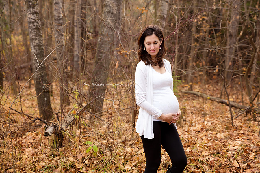 A Spanish woman with dark hair and a white shirt poses in the Millcreek ravine during Fall maternity photos in Edmonton