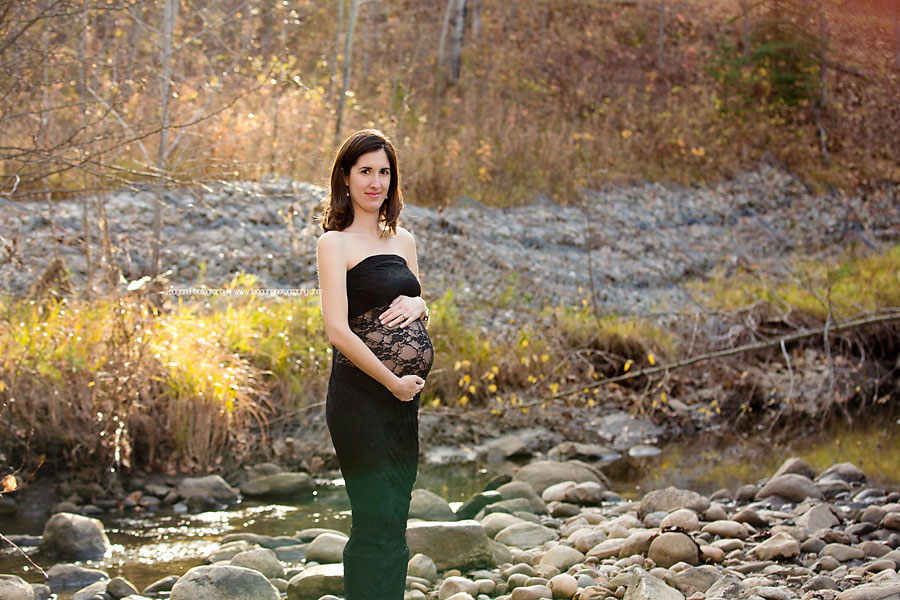 A Spanish woman with dark hair and a white shirt poses in the Millcreek ravine during Fall maternity photos in Edmonton
