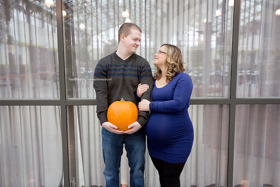 A husband holds a pumpkin next to his pregnant wife at the Enjoy Centre in St Albert during a maternity photoshoot