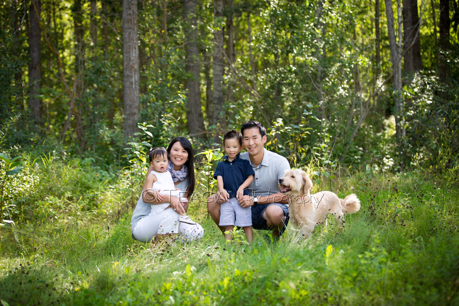 An Asian family poses together with their dog at Larch Sanctuary in Edmonton during family photos 