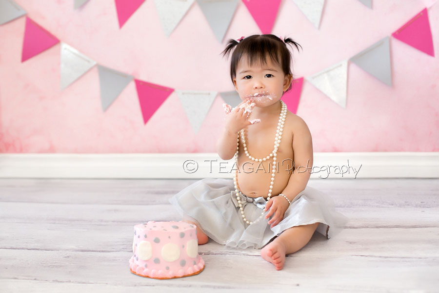 Celebrating her first birthday in Edmonton with a caks smash photo shoot is an Asian girl