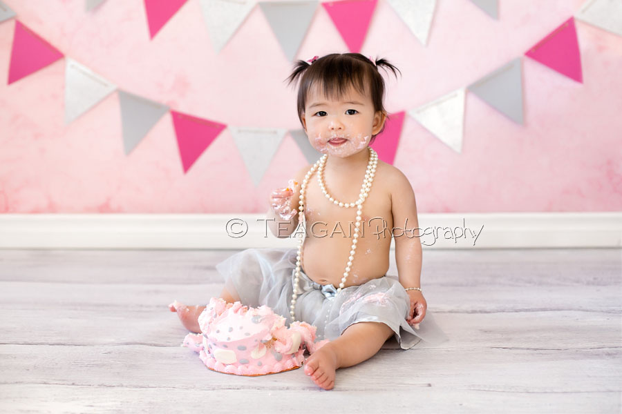 Celebrating her first birthday with a caks smash photo shoot is an Asian girl