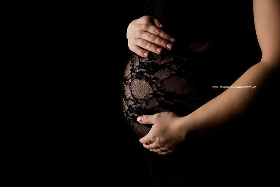Wearing black lace is a pregnant woman during a Edmonton Studio photography session  