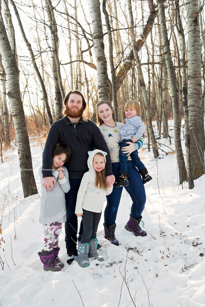 Big siblings hold their little sisters during a winter family photo shoot in Edmonton