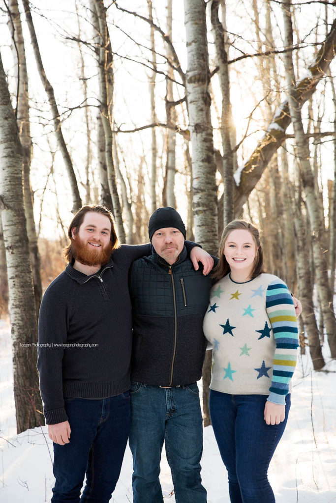 A father hugs hius two adult children in a west Edmonton forest in the winter