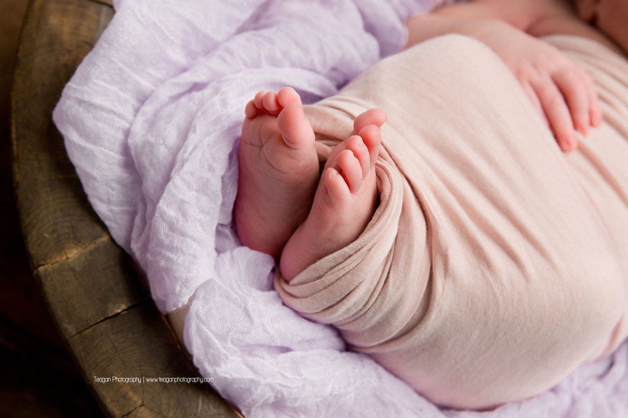 teeny baby toes peek out of a pale pink blanket