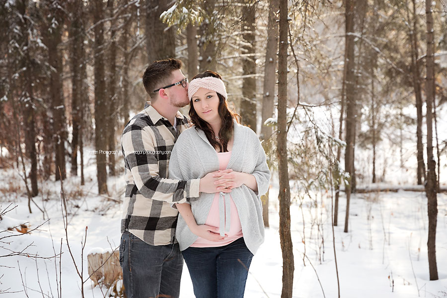 A husband and wife pose during a winter maternity photography session in Edmonton