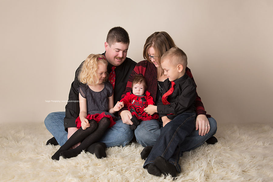 A family wearing black and red clothing sits together for a Christmas themed photoshoot in Edmonton