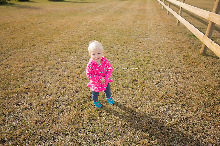 A little girl with short blonde hair runs through the dry grass in an Edmonton field
