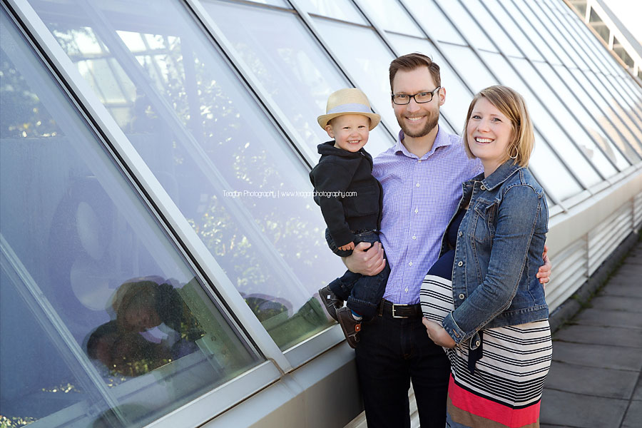 A family stands along the glass walls above the Muttart Conservatory Pyramids
