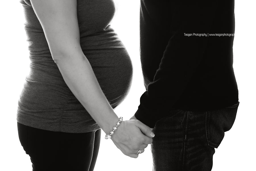 A close up photo of a couple holding hands and the mom's pregnant belly