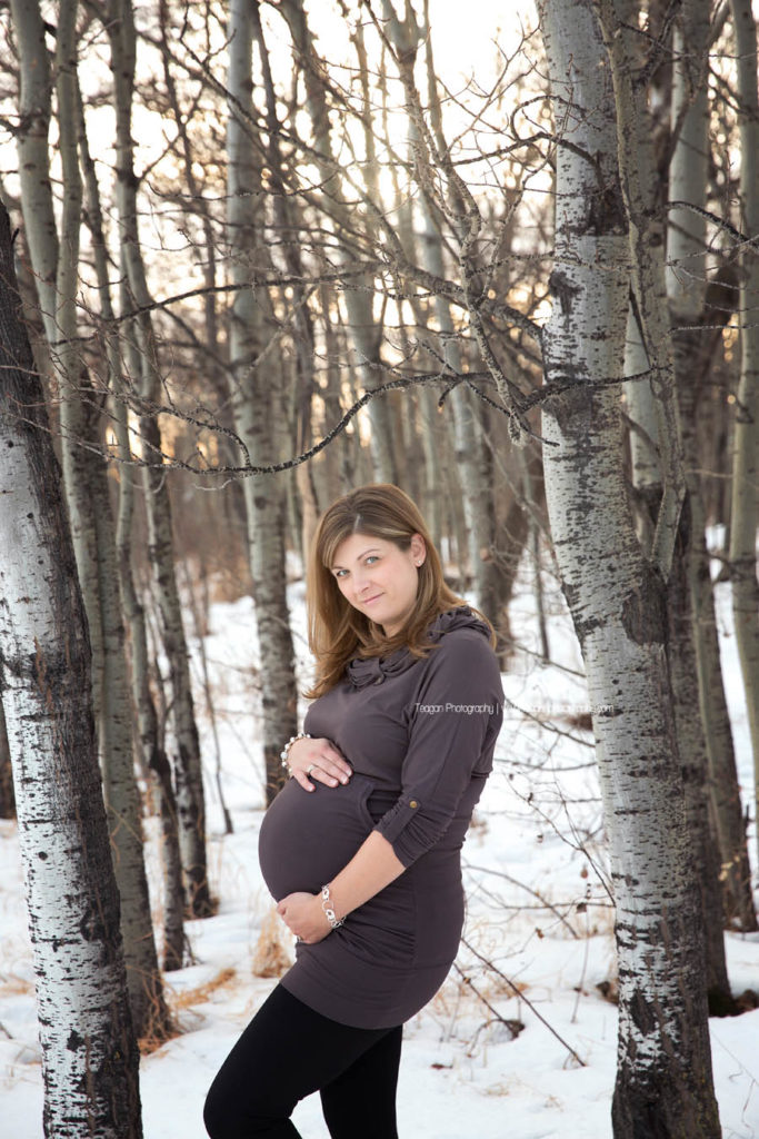 A pregnant mother celebrates her pregnancy with a winter maternity photo session in an Edmonton forest