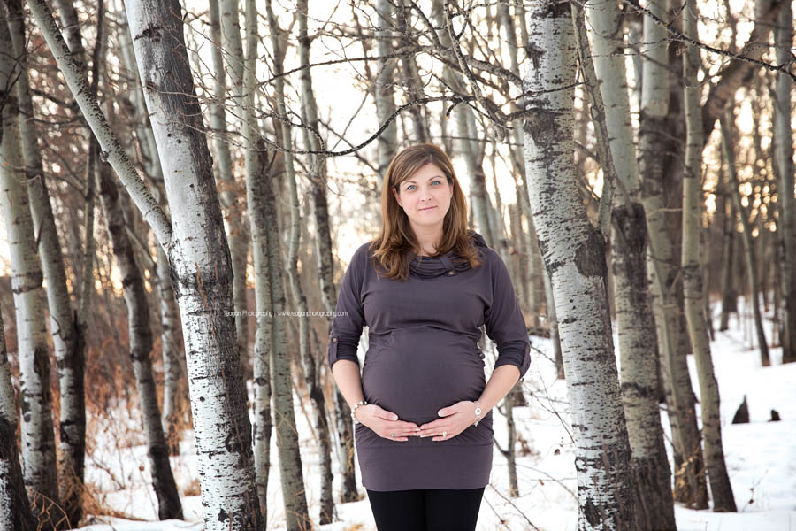 A pregnant mother celebrates her pregnancy with a winter maternity photo session in an Edmonton forest