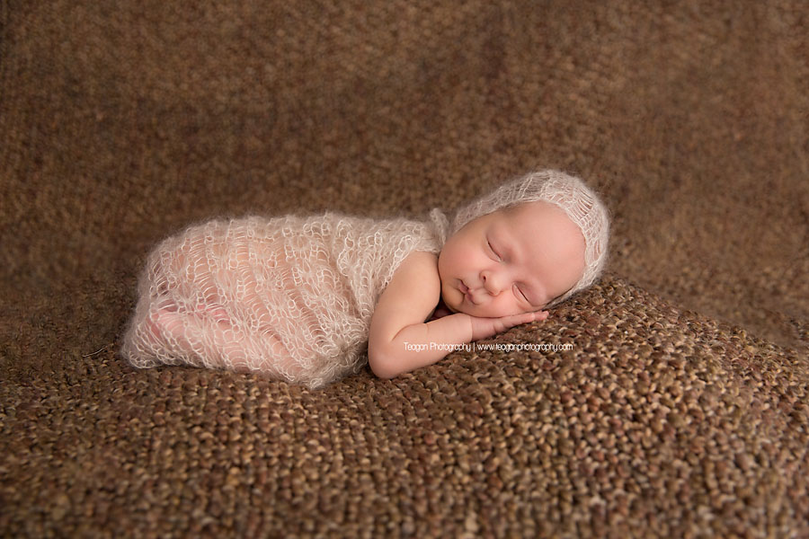 Wrapped in a delactie knit blanket is a newborn baby girl
