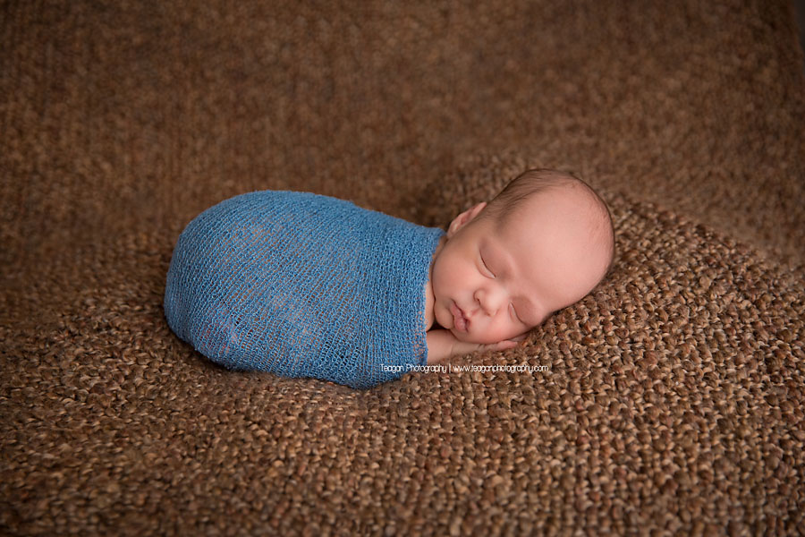 A newbron boy smiles in his sleep at an Edmonton newborn photography session