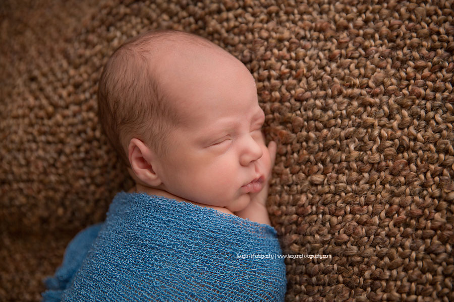 A newbron boy smiles in his sleep at an Edmonton newborn photography session