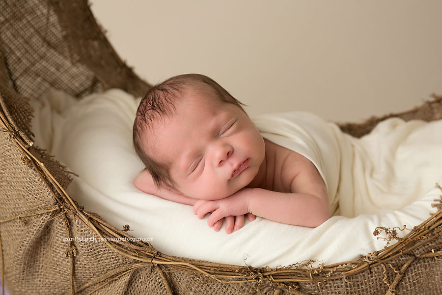 A newborn baby is wrapped in a white blanket  