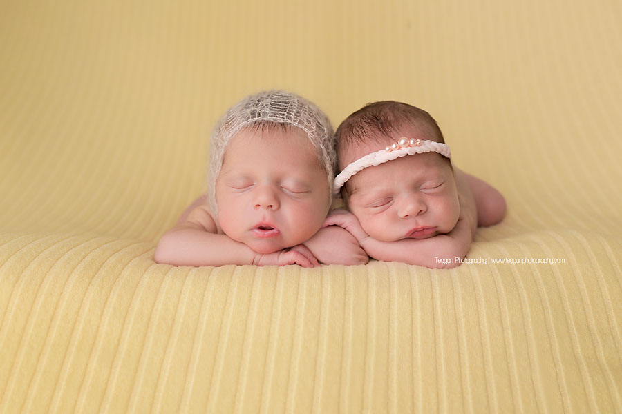 Twin baby girls sleep together on a lemon yellow blanket