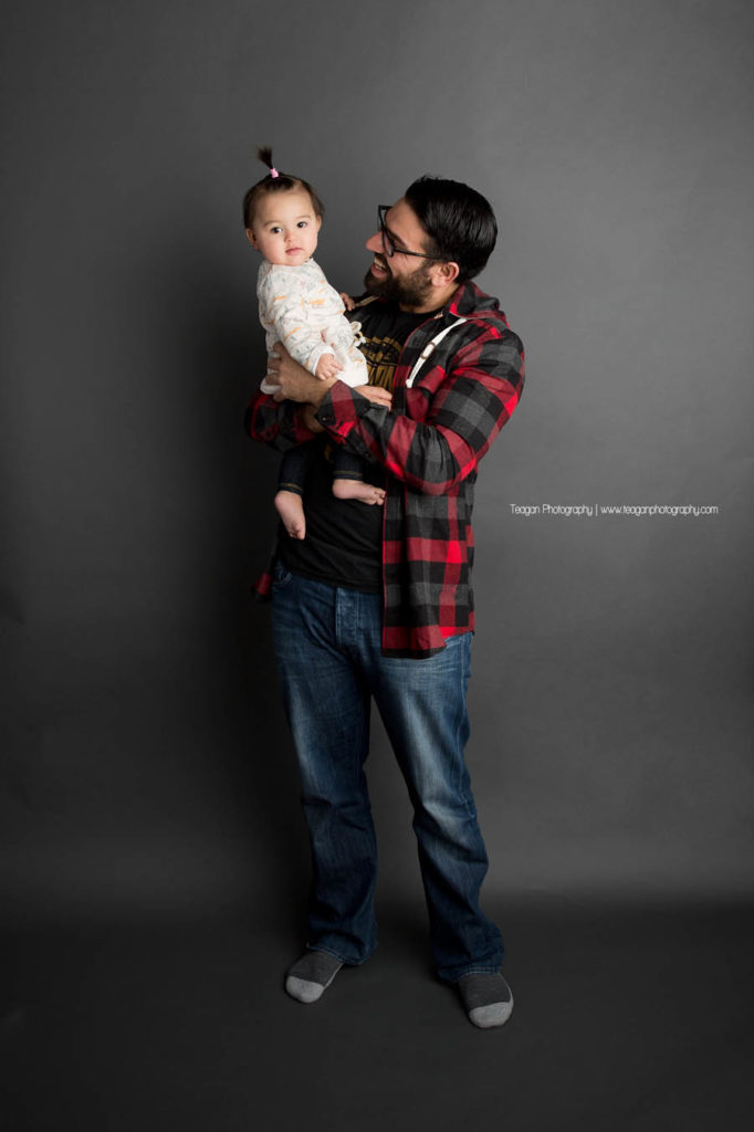 A father and baby daughter wearing red plaid giggle together during an Edmonton daddy and me photo session