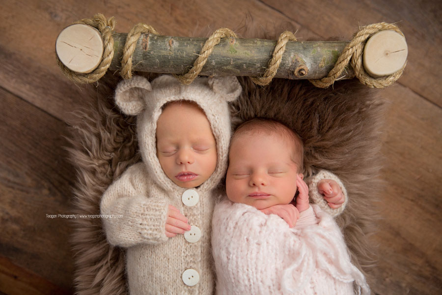 Wearing a teddy bear outfit is a newborn boy snuggling his twin sister