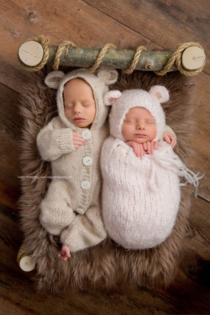 Wearing a teddy bear outfit is a newborn boy snuggling his twin sister