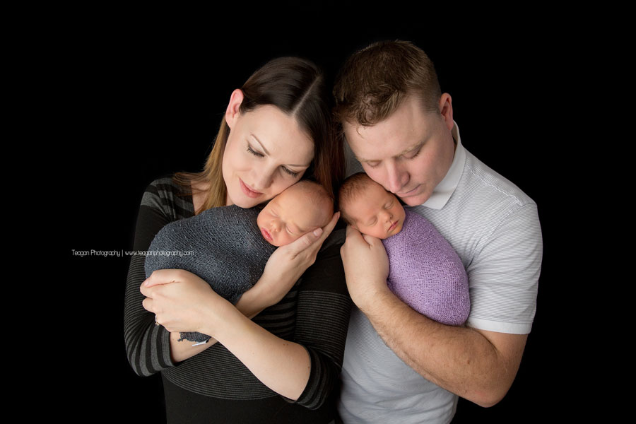 A new mother and father snuggle their twin babies during an Edmonton newborn photo session