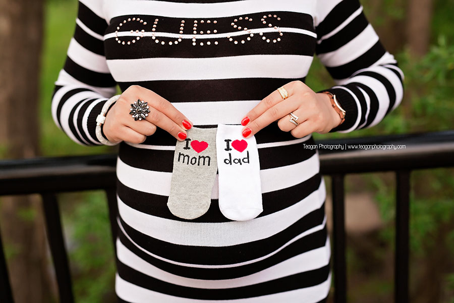 A pregnant mom holds tiny little socks to her belly