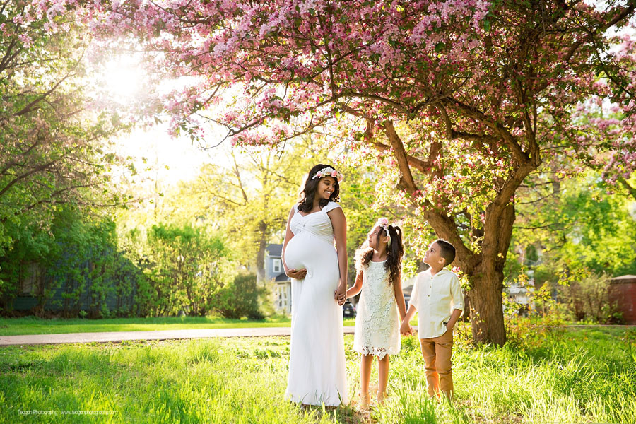 A pregnant mother poses with her two children underneath a blossoming crab apple tree in the Edmonton River valley