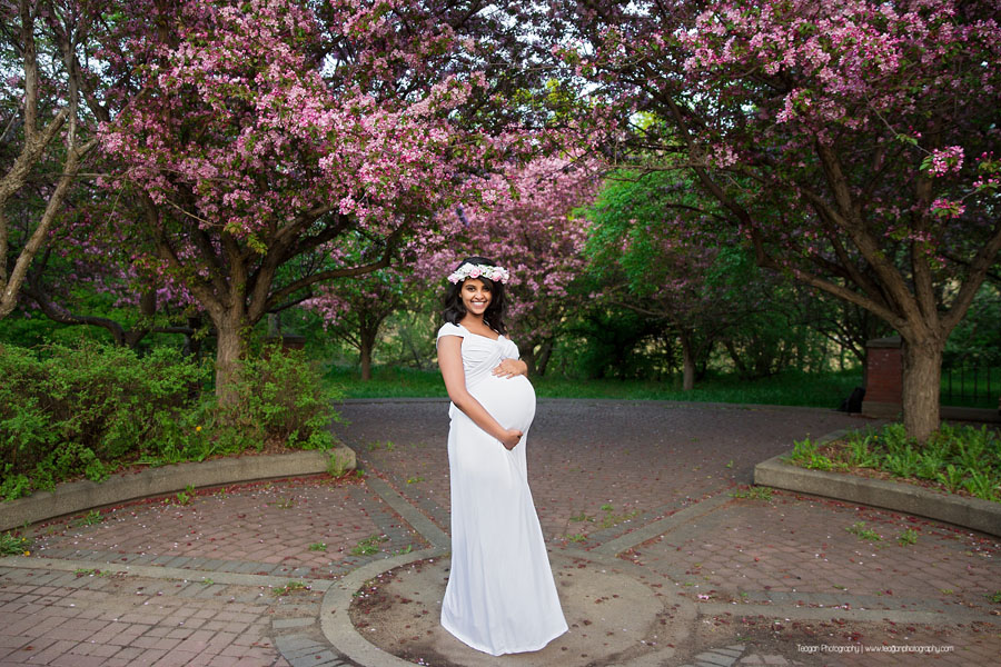 Standing in the sunshine is pregnant mother wearing a white maternity dress